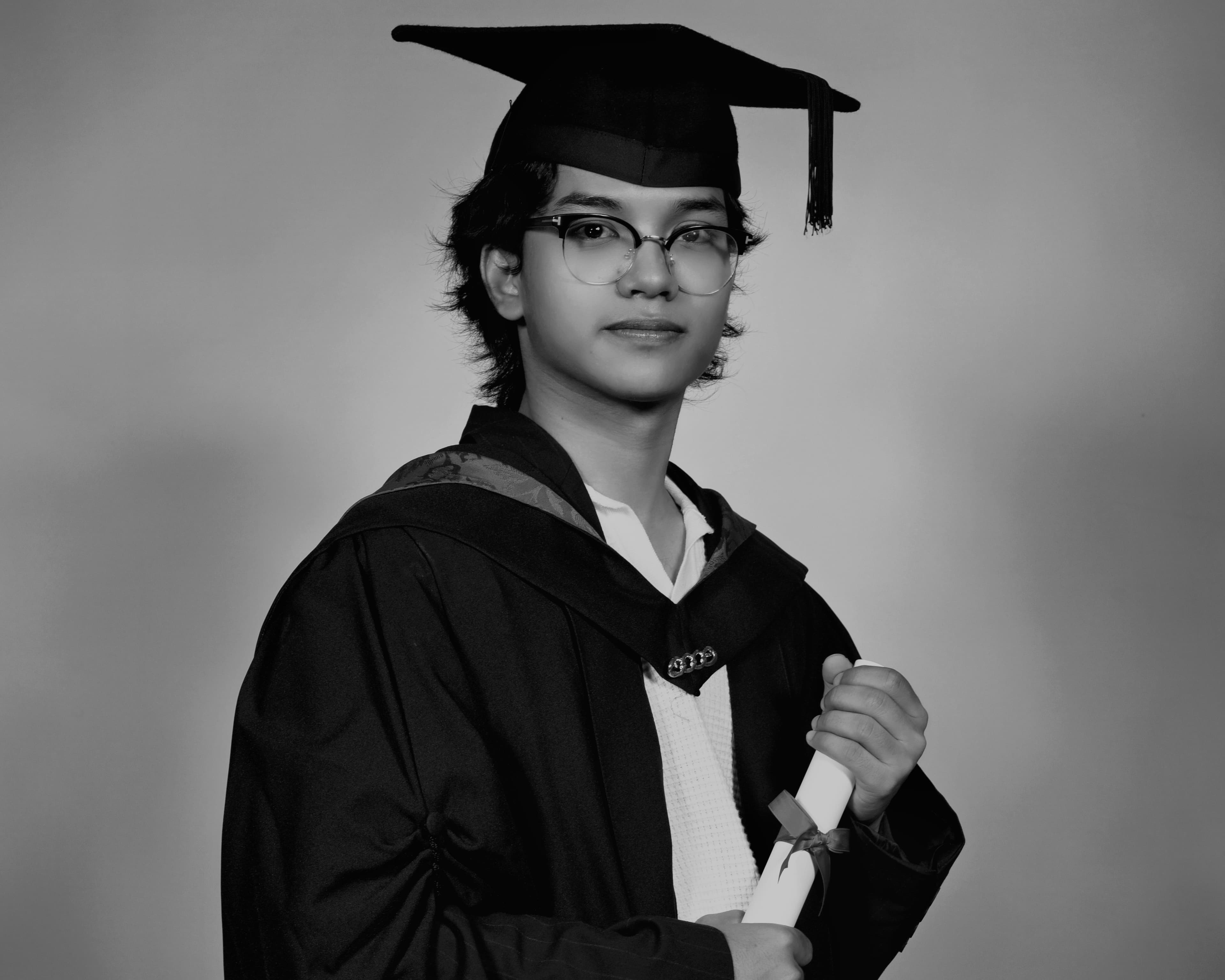 A person with graduation grown standing while holding graduation paper roll